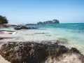 Piękne plaże i turkusowa woda, idealne miejsca w Krabi, co zobaczyć. Skały i zieleń na tle błękitnego nieba.