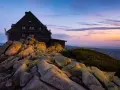 Schronisko na Szrenicy, ile się wchodzi, by podziwiać ten widok o wschodzie słońca. Skały i kosodrzewina na tle pastelowego nieba.