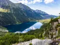 Widok na Morskie Oko, perłę polskich gór Tatr. Lśniąca tafla jeziora odbija błękitne niebo i otaczające je szczyty.
