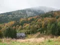 Jesienny las w Górach Sowich otula mgłą szczyty. Na zboczu malowniczo położony dom, jak jedna z urokliwych miejscowości regionu.