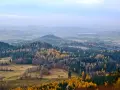 Jesienny krajobraz z kolorowymi drzewami na tle mglistych, niskich gór w Polsce.