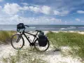 Rower z sakwami gotowy na przygodę. Trasa rowerowa wzdłuż Bałtyku zapowiada się wspaniale, z piaszczystą plażą i szumem fal.