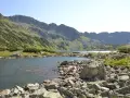Malownicze jezioro w Tatrach, idealne na szlaki turystyczne Zakopane. Kamieniste brzegi i zielone zbocza gór tworzą piękny krajobraz.
