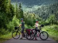 Para rowerzystów na tle górskiego lasu, gotowa na odkrywanie tras rowerowych Tatr.