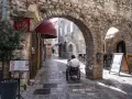 Mężczyzna na wózku inwalidzkim przemierza urokliwe uliczki budva stare miasto, podziwiając kamienne łuki i zabytkową architekturę.
