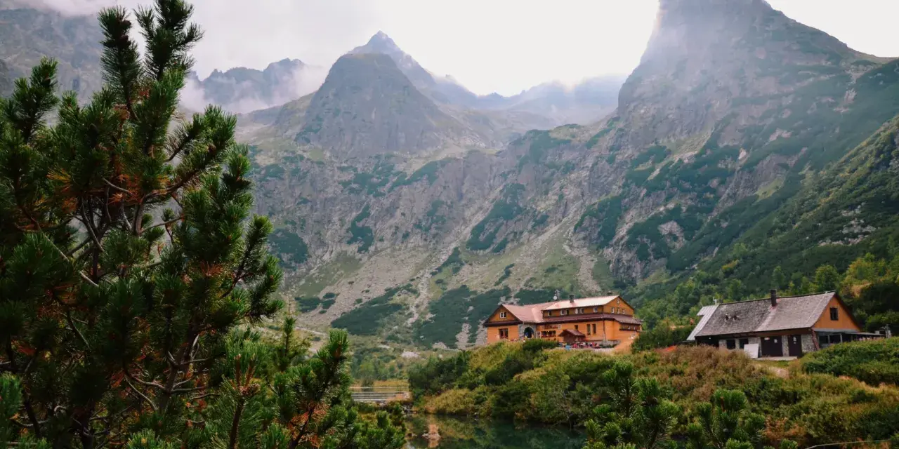 Tatry Wysokie Słowacja: schroniska nad jeziorem, otoczone zielenią i majestatycznymi szczytami gór.