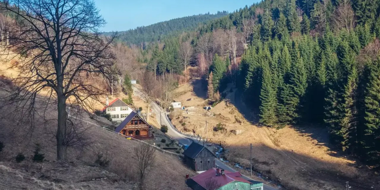 Góry, gdzie są? W dolinie, wśród lasów i domków, widać kilka uroczych chat.