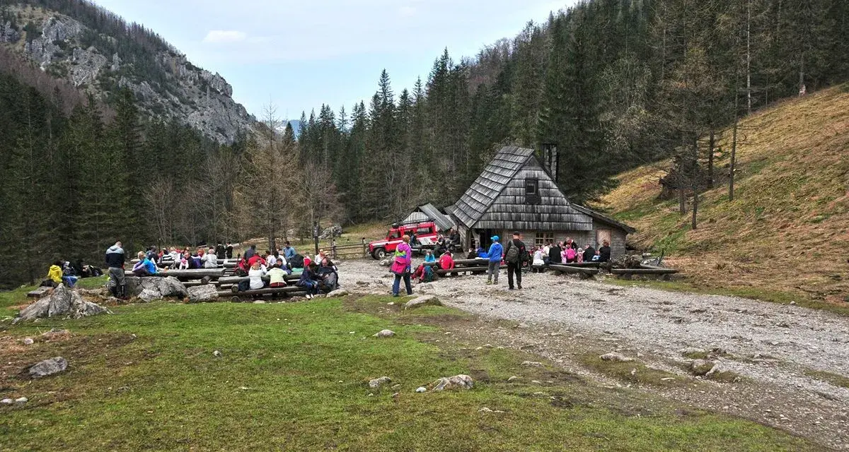 Ludzie odpoczywają przy bacówce na trasie Dolina Strążyska. W tle las i góry.