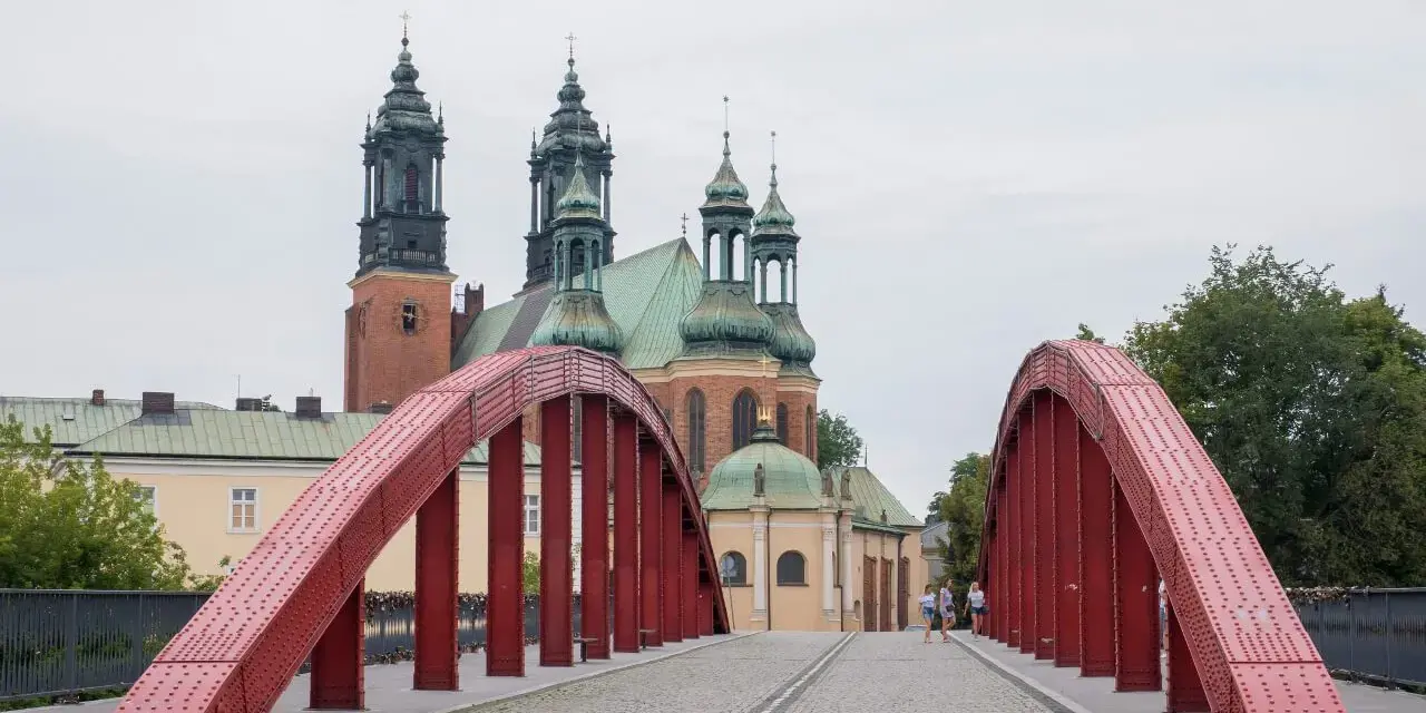 Czerwony most na Ostrowie Tumskim w Poznaniu, w tle katedra. Idealne miejsce na spacer, odkrywając poznańskie atrakcje dla dorosłych.