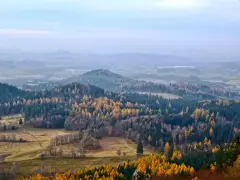 Jesienny krajobraz z kolorowymi drzewami na tle mglistych, niskich gór w Polsce.