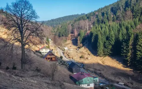 Góry, gdzie są? W dolinie, wśród lasów i domków, widać kilka uroczych chat.
