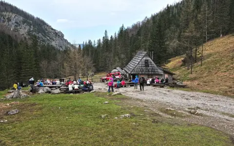 Ludzie odpoczywają przy bacówce na trasie Dolina Strążyska. W tle las i góry.