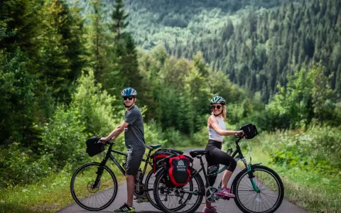 Para rowerzystów na tle górskiego lasu, gotowa na odkrywanie tras rowerowych Tatr.