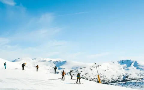 Narciarze na ośnieżonych stokach Sierra Nevada. Piękna zima w Hiszpanii, błękitne niebo i słońce.