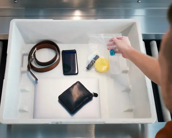 Na lotnisku wyjmujesz z bagażu podręcznego telefon, portfel, pasek i kosmetyki w przezroczystej torebce, pamiętając o **limicie płynów w bagażu podręcznym**.