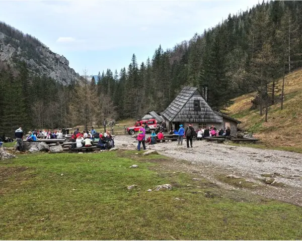 Ludzie odpoczywają przy bacówce na trasie Dolina Strążyska. W tle las i góry.