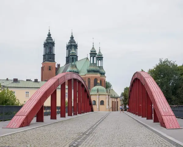 Czerwony most na Ostrowie Tumskim w Poznaniu, w tle katedra. Idealne miejsce na spacer, odkrywając poznańskie atrakcje dla dorosłych.