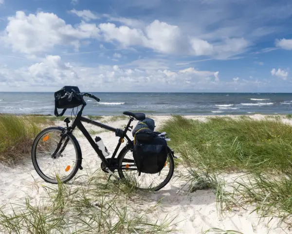 Rower z sakwami gotowy na przygodę. Trasa rowerowa wzdłuż Bałtyku zapowiada się wspaniale, z piaszczystą plażą i szumem fal.