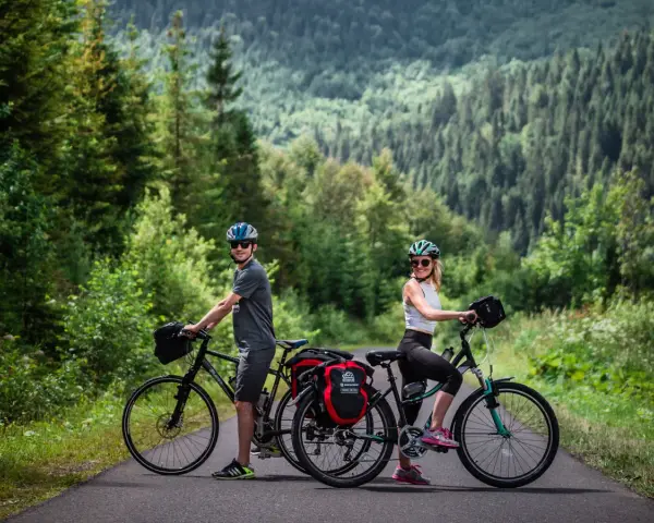 Para rowerzystów na tle górskiego lasu, gotowa na odkrywanie tras rowerowych Tatr.