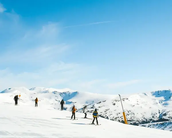 Narciarze na ośnieżonych stokach Sierra Nevada. Piękna zima w Hiszpanii, błękitne niebo i słońce.