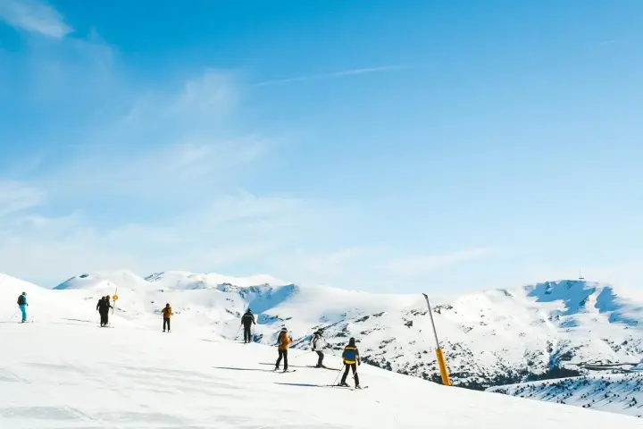 Narciarze na ośnieżonych stokach Sierra Nevada. Piękna zima w Hiszpanii, błękitne niebo i słońce.