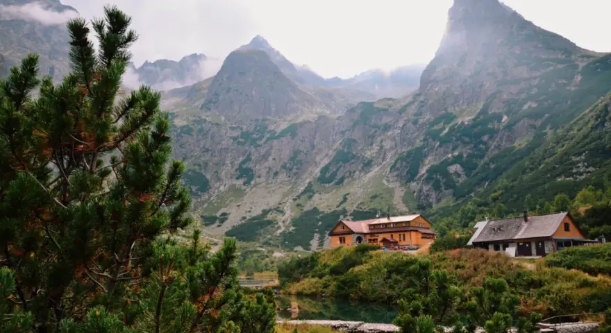 Tatry Wysokie Słowacja: schroniska nad jeziorem, otoczone zielenią i majestatycznymi szczytami gór.