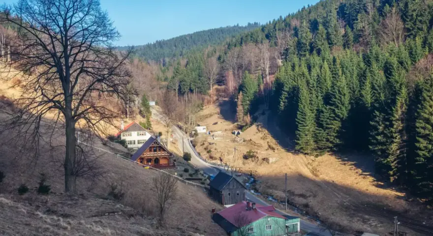 Góry, gdzie są? W dolinie, wśród lasów i domków, widać kilka uroczych chat.