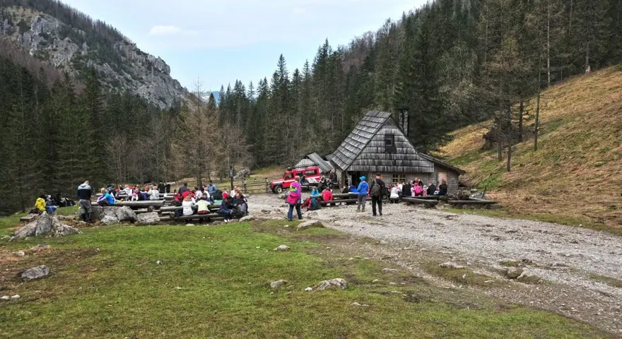 Ludzie odpoczywają przy bacówce na trasie Dolina Strążyska. W tle las i góry.