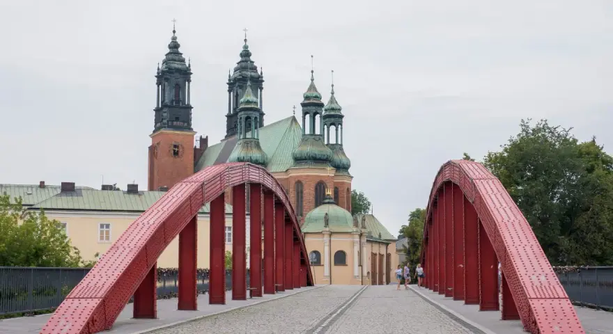 Czerwony most na Ostrowie Tumskim w Poznaniu, w tle katedra. Idealne miejsce na spacer, odkrywając poznańskie atrakcje dla dorosłych.
