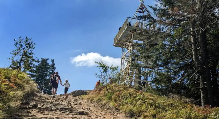 Rodzina wędruje kamienistym szlakiem na Baranią Górę. W oddali widać wieżę widokową.