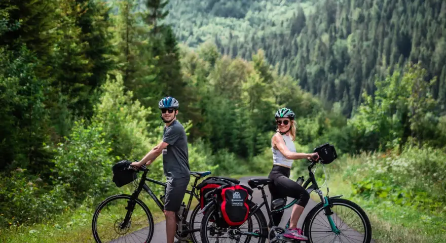 Para rowerzystów na tle górskiego lasu, gotowa na odkrywanie tras rowerowych Tatr.