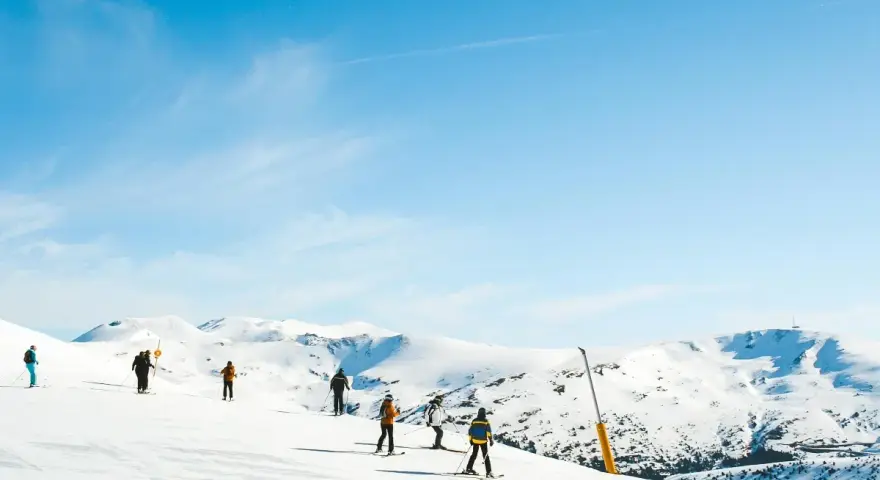 Narciarze na ośnieżonych stokach Sierra Nevada. Piękna zima w Hiszpanii, błękitne niebo i słońce.