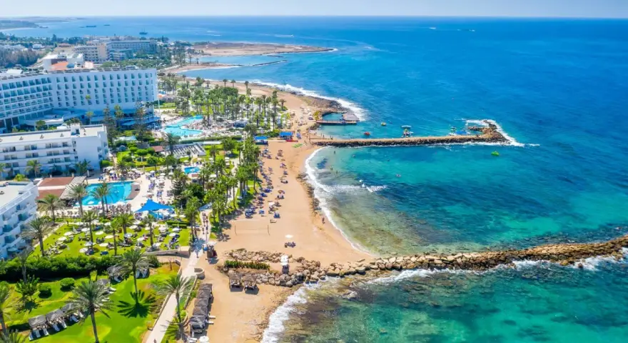 Słoneczna plaża z hotelami i basenami, turkusowe morze. Czy to Pafos czy Larnaka, wakacje marzeń!