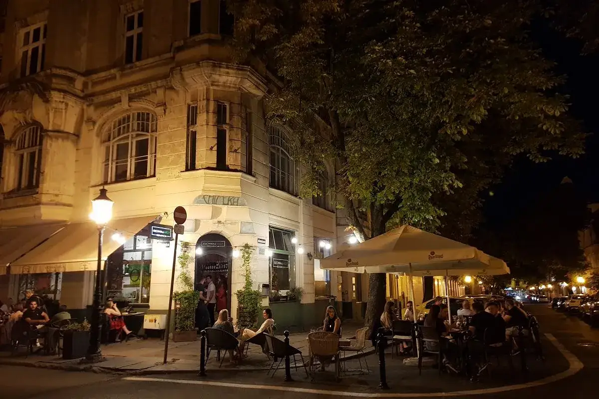 Wieczorny Poznań: przytulny ogródek restauracji z ludźmi relaksującymi się przy stolikach. Idealne poznańskie atrakcje dla dorosłych szukających chwili wytchnienia.
