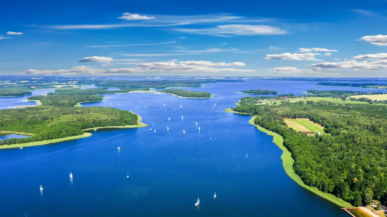 Mazury co warto zobaczyć: malownicze jeziora, zielone wyspy i żaglówki na błękitnej tafli. Idealne miejsce na relaks i aktywne spędzanie czasu.