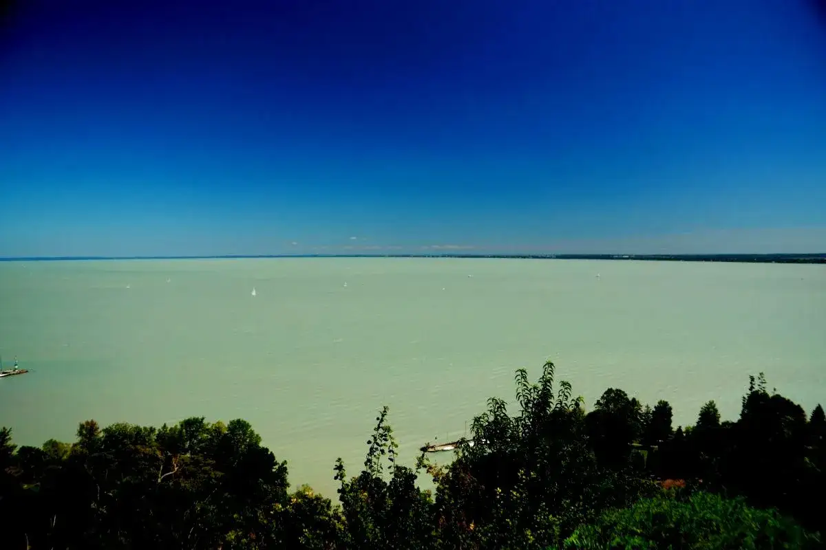 Widok na spokojny Balaton, gdzie żagl&oacute;wki suną po turkusowej wodzie. To jedno z najpiękniejszych miejsc nad Balatonem.